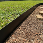 Black metal garden edging separating lawn from mulched garden bed