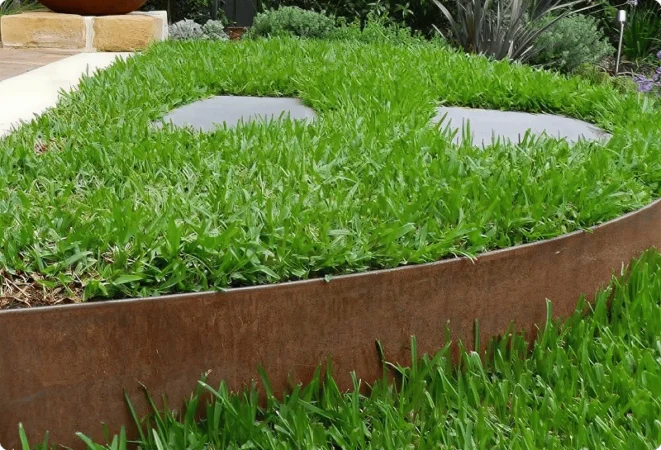 Curved corten steel garden edging forming raised garden bed with lush green grass