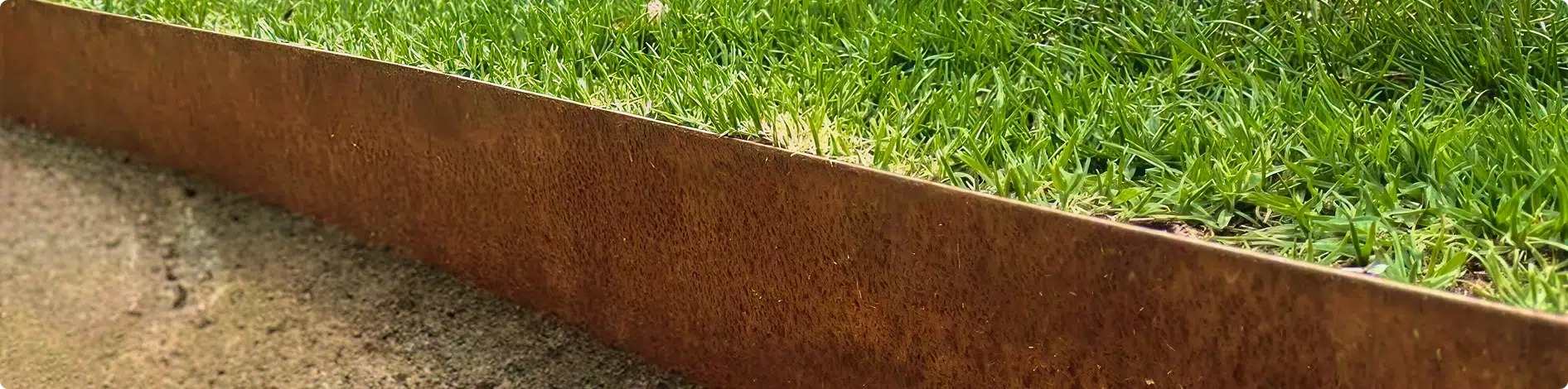 Rusty corten steel garden edging separating lawn from a path