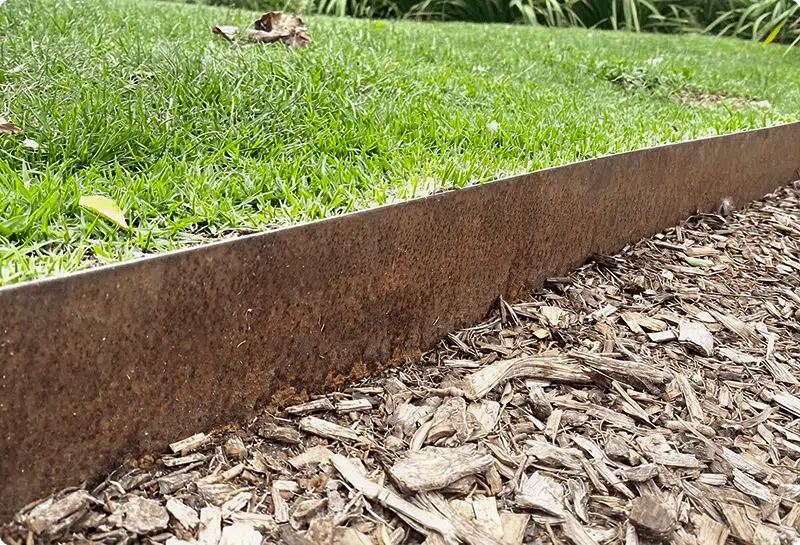 Rusty corten steel garden edging separating lawn from mulch