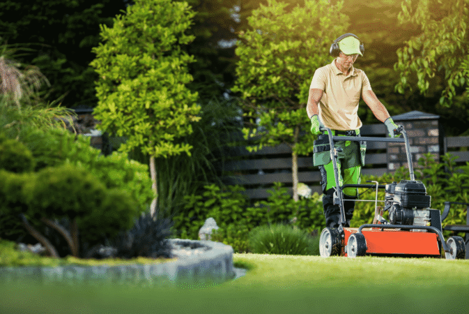 A person mowing a lawn in a garden, illustrating garden maintenance services.